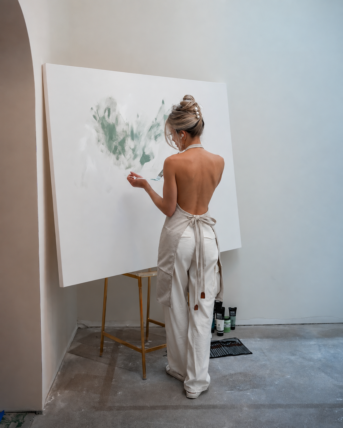 The artist seen from behind, painting on a white wall